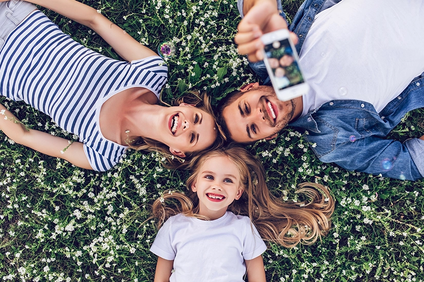 Rodzina leżąca na trawie robiąca zdjęcia smartfonem